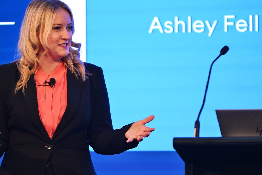 Ashley Fell presenting beside a lectern with her name on screen