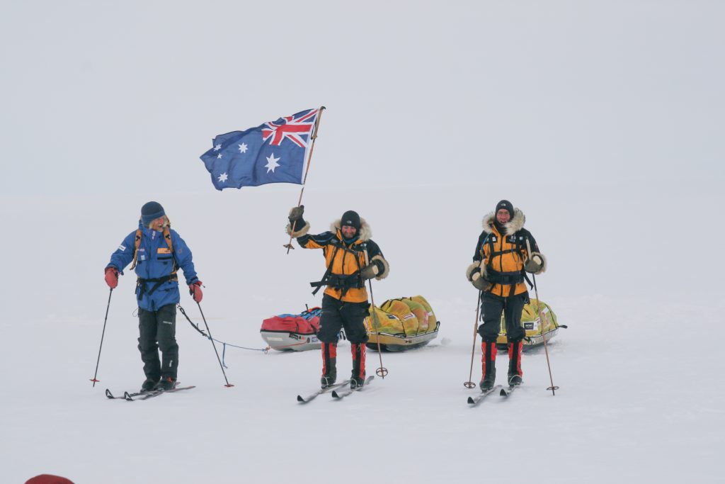 James Castrission and teammates skiing with an Australian flag in Antarctica