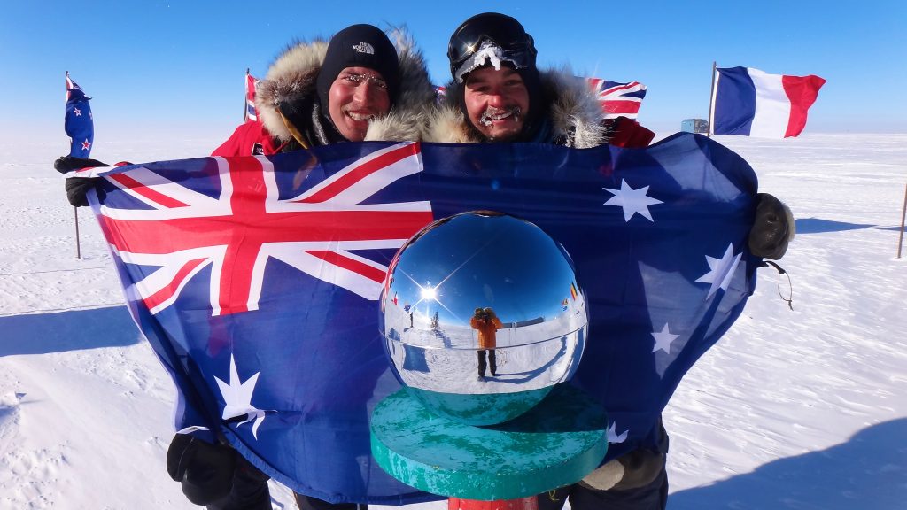 James Castrission and a teammate celebrating with an Australian flag at the South Pole