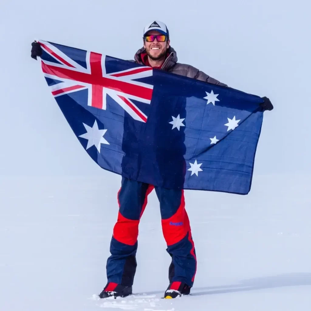 Daniel Bull holding an Australian flag in a polar landscape