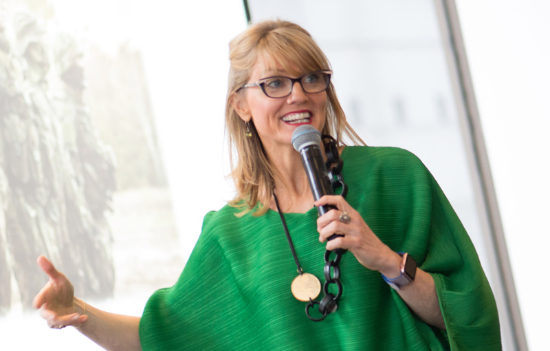 Georgia Murch speaking into a microphone in a green outfit