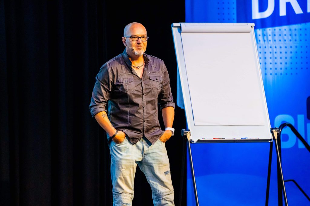 Justin Herald standing on stage beside a flipchart