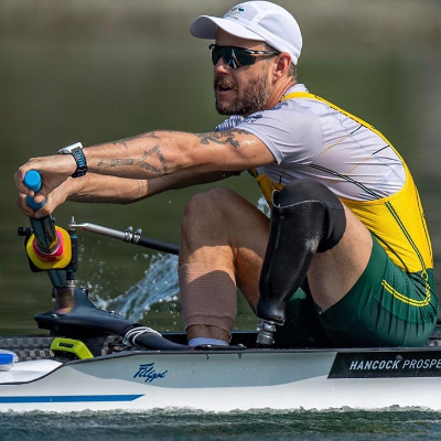 Jed Altschwager rowing on the water wearing a prosthetic leg