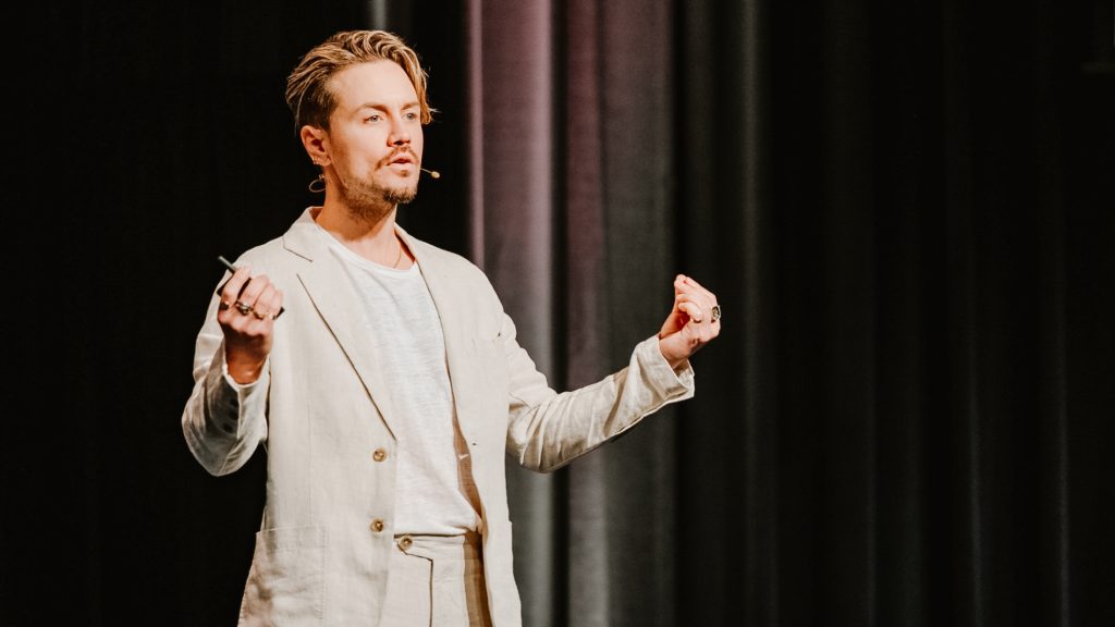 Mitch Wallis presenting on a theatre stage