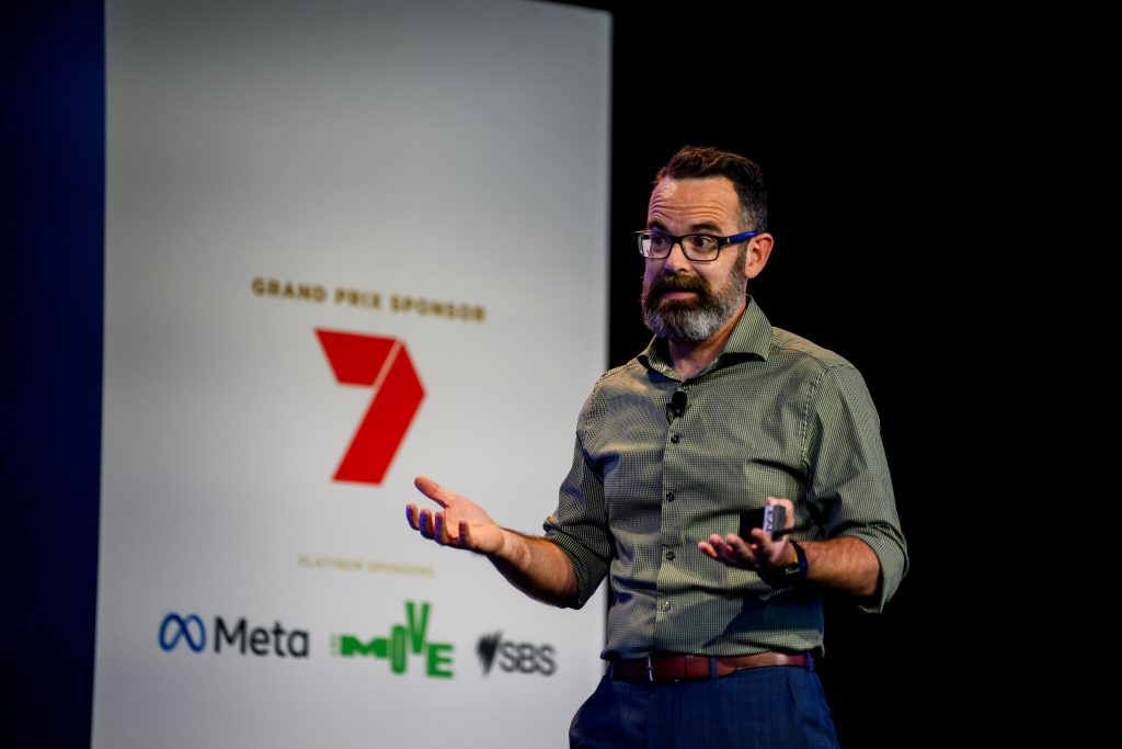 Paul Watkins speaking beside a presentation slide