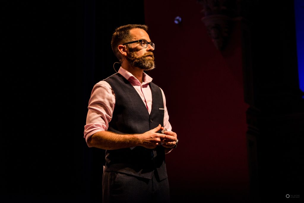 Paul Watkins speaking on a theatre stage