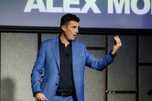 Alex Moffat presenting on stage