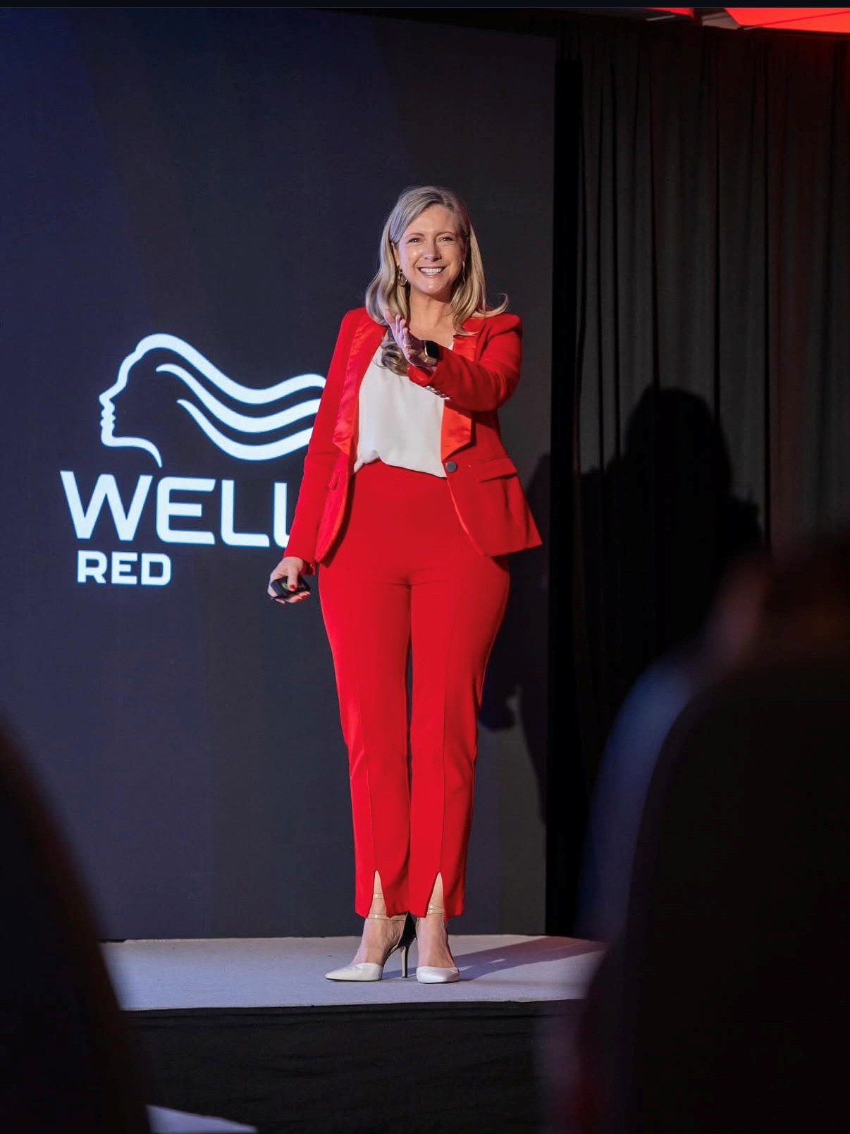Kirryn Zerna business speaker in red suit WELL RED backdrop